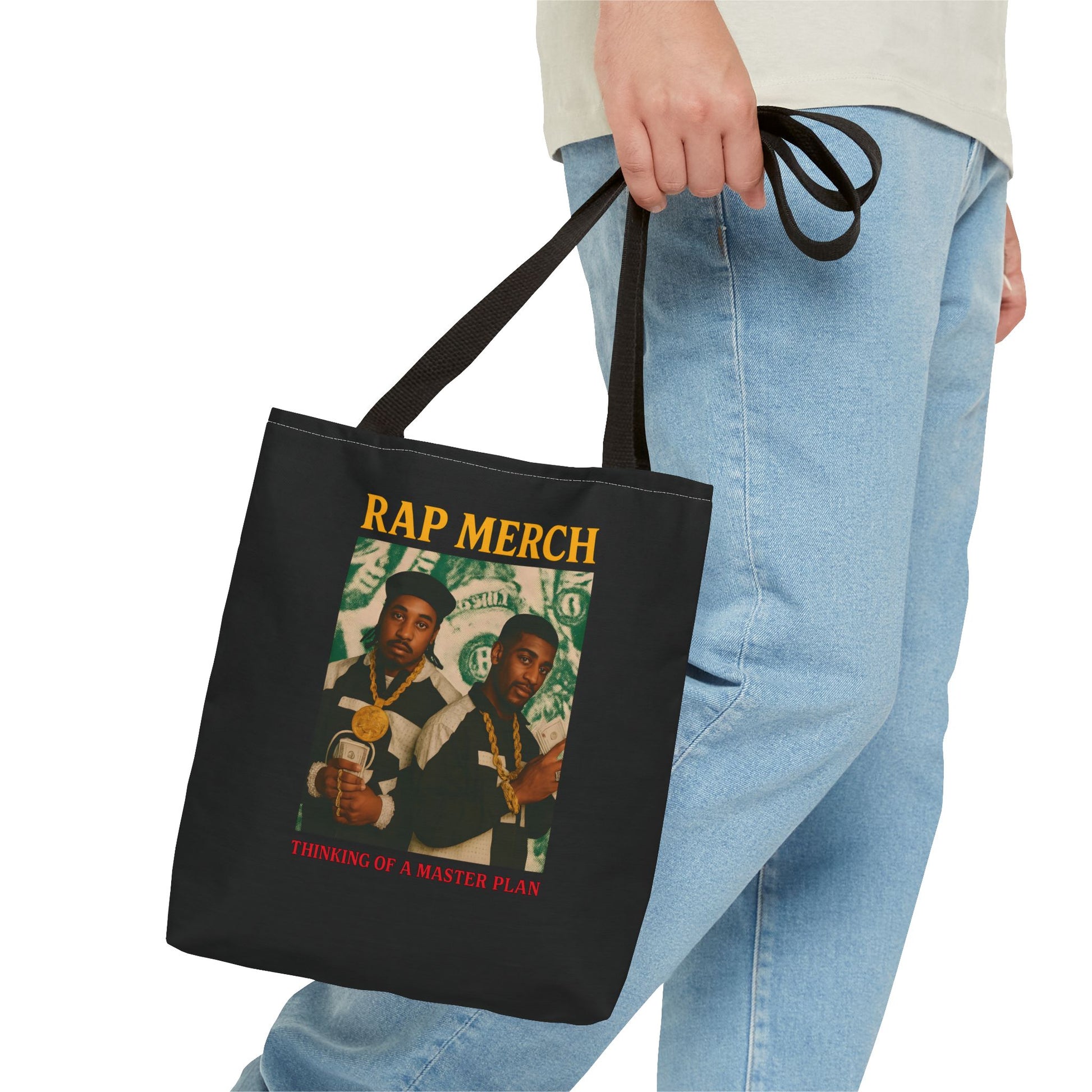 Black tote bag with graphic design and text held by a person wearing light blue jeans.